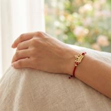 Гривна с червен конец и 14 карата златен елемент корона с гравирано послание