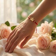 Гривна с червен конец и 14 карата златен елемент корона с гравирано послание