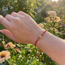 Гривна с червен конец и 14 карата златен елемент детелинка