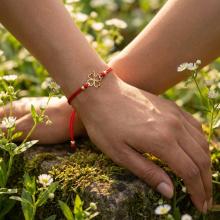 Гривна с червен конец и 14 карата златен елемент детелинка