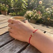 Гривна с червен конец и 14 карата златен елемент детелинка