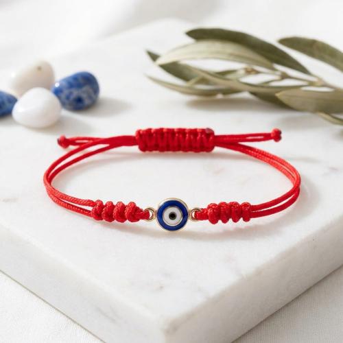 Гривна с червен конец и златен елемент синьо око