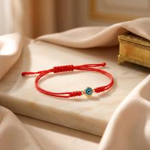 Гривна с червен конец и златен елемент синьо око