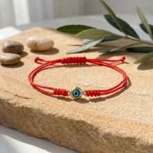 Гривна с червен конец и златен елемент синьо око